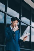 Businessman using tablet and enjoying in coffee break in front of the the corporation. Business, lifestyle concept photo