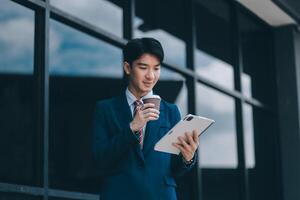 Businessman using tablet and enjoying in coffee break in front of the the corporation. Business, lifestyle concept photo