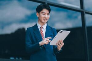 Businessman using tablet and enjoying in coffee break in front of the the corporation. Business, lifestyle concept photo