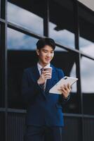 Businessman using tablet and enjoying in coffee break in front of the the corporation. Business, lifestyle concept photo