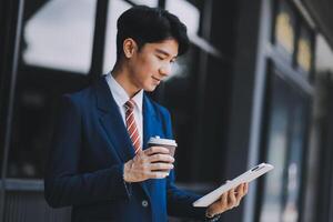 Businessman using tablet and enjoying in coffee break in front of the the corporation. Business, lifestyle concept photo