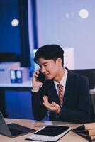 Serious trader using mobile phone app on smartphone for checking stock trading data analysis concept, focused businessman holding cellphone working in office with financial graph on computer monitors photo