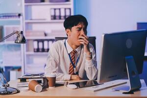Businessman workaholic sit at the computer working late at night yawn tired and sleeping in the office,Hard work in the later time concept photo
