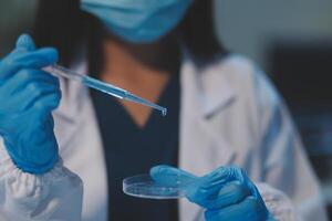 Group of dedicated scientist conduct chemical experiment in medical laboratory, carefully drop precise amount of liquid from pipette into test tube for vaccine drug or antibiotic development. Neoteric photo