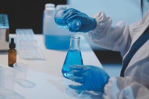 Group of dedicated scientist conduct chemical experiment in medical laboratory, carefully drop precise amount of liquid from pipette into test tube for vaccine drug or antibiotic development. Neoteric photo