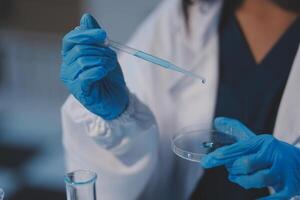 Group of dedicated scientist conduct chemical experiment in medical laboratory, carefully drop precise amount of liquid from pipette into test tube for vaccine drug or antibiotic development. Neoteric photo