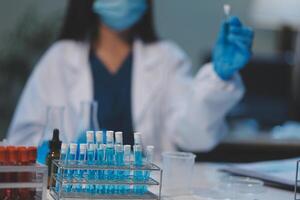Group of dedicated scientist conduct chemical experiment in medical laboratory, carefully drop precise amount of liquid from pipette into test tube for vaccine drug or antibiotic development. Neoteric photo
