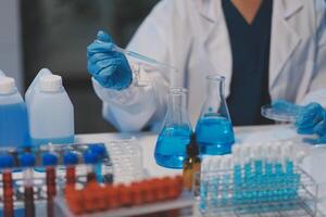 Group of dedicated scientist conduct chemical experiment in medical laboratory, carefully drop precise amount of liquid from pipette into test tube for vaccine drug or antibiotic development. Neoteric photo