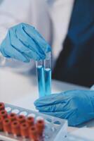 Group of dedicated scientist conduct chemical experiment in medical laboratory, carefully drop precise amount of liquid from pipette into test tube for vaccine drug or antibiotic development. Neoteric photo