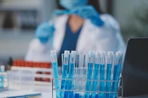 Group of dedicated scientist conduct chemical experiment in medical laboratory, carefully drop precise amount of liquid from pipette into test tube for vaccine drug or antibiotic development. Neoteric photo
