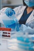 Group of dedicated scientist conduct chemical experiment in medical laboratory, carefully drop precise amount of liquid from pipette into test tube for vaccine drug or antibiotic development. Neoteric photo
