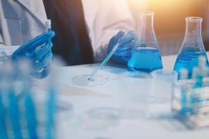 Group of dedicated scientist conduct chemical experiment in medical laboratory, carefully drop precise amount of liquid from pipette into test tube for vaccine drug or antibiotic development. Neoteric photo