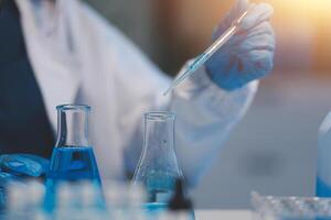 Group of dedicated scientist conduct chemical experiment in medical laboratory, carefully drop precise amount of liquid from pipette into test tube for vaccine drug or antibiotic development. Neoteric photo
