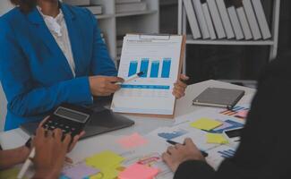 Meeting with business partners to discuss financial advisors to analyze market growth charts in business reports and plan investment strategies. photo