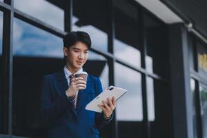 Businessman using tablet and enjoying in coffee break in front of the the corporation. Business, lifestyle concept photo