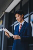 Businessman using tablet and enjoying in coffee break in front of the the corporation. Business, lifestyle concept photo