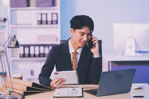 Serious trader using mobile phone app on smartphone for checking stock trading data analysis concept, focused businessman holding cellphone working in office with financial graph on computer monitors photo