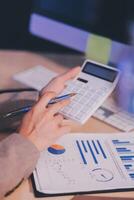 Business accounting concept Businessman uses calculator with laptop computer Budget and borrowed paper Calculate expenses, expenses, taxes online, manage company budgets, close-up images photo