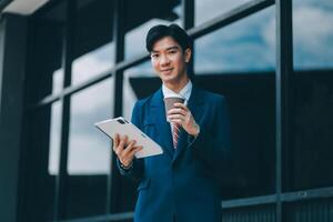Businessman using tablet and enjoying in coffee break in front of the the corporation. Business, lifestyle concept photo