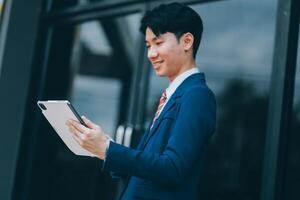 Businessman using tablet and enjoying in coffee break in front of the the corporation. Business, lifestyle concept photo