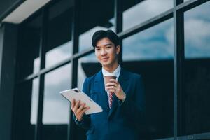 Businessman using tablet and enjoying in coffee break in front of the the corporation. Business, lifestyle concept photo