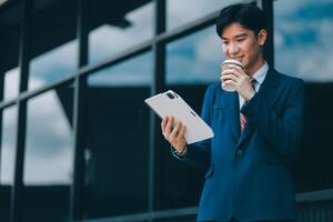Businessman using tablet and enjoying in coffee break in front of the the corporation. Business, lifestyle concept photo