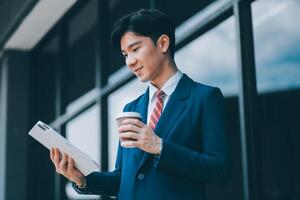 Businessman using tablet and enjoying in coffee break in front of the the corporation. Business, lifestyle concept photo