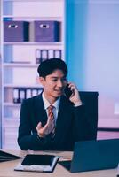 Serious trader using mobile phone app on smartphone for checking stock trading data analysis concept, focused businessman holding cellphone working in office with financial graph on computer monitors photo