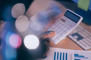 Business accounting concept Businessman uses calculator with laptop computer Budget and borrowed paper Calculate expenses, expenses, taxes online, manage company budgets, close-up images photo