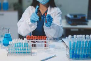 Group of dedicated scientist conduct chemical experiment in medical laboratory, carefully drop precise amount of liquid from pipette into test tube for vaccine drug or antibiotic development. Neoteric photo