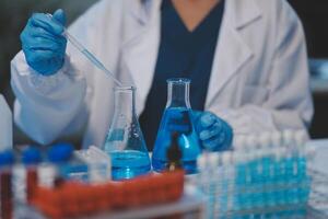 Group of dedicated scientist conduct chemical experiment in medical laboratory, carefully drop precise amount of liquid from pipette into test tube for vaccine drug or antibiotic development. Neoteric photo