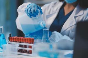 Group of dedicated scientist conduct chemical experiment in medical laboratory, carefully drop precise amount of liquid from pipette into test tube for vaccine drug or antibiotic development. Neoteric photo