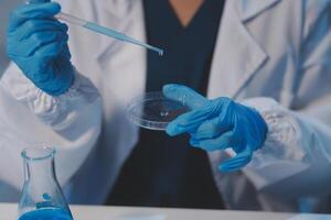 Group of dedicated scientist conduct chemical experiment in medical laboratory, carefully drop precise amount of liquid from pipette into test tube for vaccine drug or antibiotic development. Neoteric photo