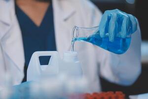 Group of dedicated scientist conduct chemical experiment in medical laboratory, carefully drop precise amount of liquid from pipette into test tube for vaccine drug or antibiotic development. Neoteric photo
