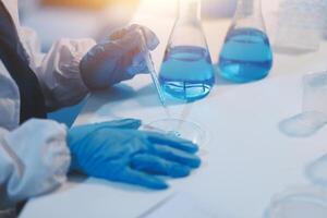Group of dedicated scientist conduct chemical experiment in medical laboratory, carefully drop precise amount of liquid from pipette into test tube for vaccine drug or antibiotic development. Neoteric photo