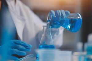 Group of dedicated scientist conduct chemical experiment in medical laboratory, carefully drop precise amount of liquid from pipette into test tube for vaccine drug or antibiotic development. Neoteric photo