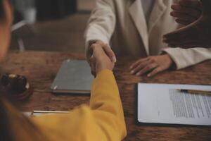 Lawyer shaking hands with a client making about documents, contracts, agreements, cooperation agreements with a female client at the lawyer's desk and a hammer at the table. photo