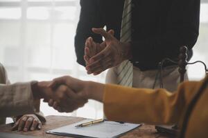 Lawyer shaking hands with a client making about documents, contracts, agreements, cooperation agreements with a female client at the lawyer's desk and a hammer at the table. photo
