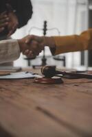 Lawyer shaking hands with a client making about documents, contracts, agreements, cooperation agreements with a female client at the lawyer's desk and a hammer at the table. photo