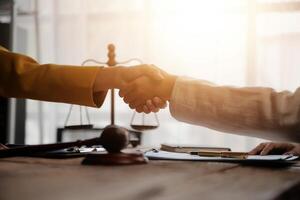 Lawyer shaking hands with a client making about documents, contracts, agreements, cooperation agreements with a female client at the lawyer's desk and a hammer at the table. photo