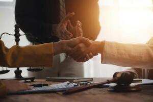 Lawyer shaking hands with a client making about documents, contracts, agreements, cooperation agreements with a female client at the lawyer's desk and a hammer at the table. photo