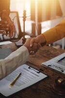 Lawyer shaking hands with a client making about documents, contracts, agreements, cooperation agreements with a female client at the lawyer's desk and a hammer at the table. photo