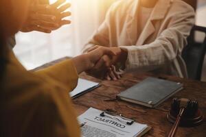 Lawyer shaking hands with a client making about documents, contracts, agreements, cooperation agreements with a female client at the lawyer's desk and a hammer at the table. photo