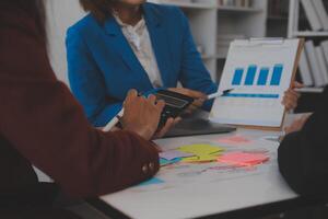 Meeting with business partners to discuss financial advisors to analyze market growth charts in business reports and plan investment strategies. photo