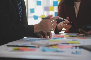 Meeting with business partners to discuss financial advisors to analyze market growth charts in business reports and plan investment strategies. photo