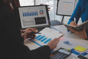 Meeting with business partners to discuss financial advisors to analyze market growth charts in business reports and plan investment strategies. photo
