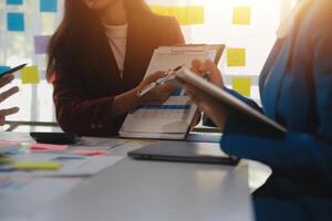 Meeting with business partners to discuss financial advisors to analyze market growth charts in business reports and plan investment strategies. photo