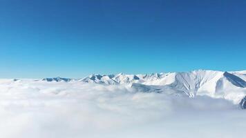 Static view snowy mountains with mist and clouds form layers below snowy peaks.. Copy space banner time lapse of forming passing clouds in mountains. Kazbegi. Georgia caucasus mountains range video