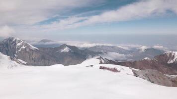 Aerial static zoom in view snowy caucasus mountains range from mount Kazbek saddle. Elbrus side view.Georgian - Russian border line zone. Beautiful sunny mountains background video