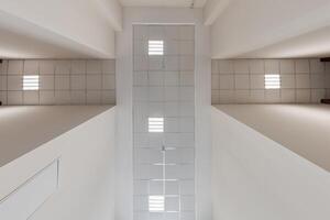 cassette stretched or suspended ceiling with square halogen spots lamps and drywall construction in empty room in house or office. Looking up view photo